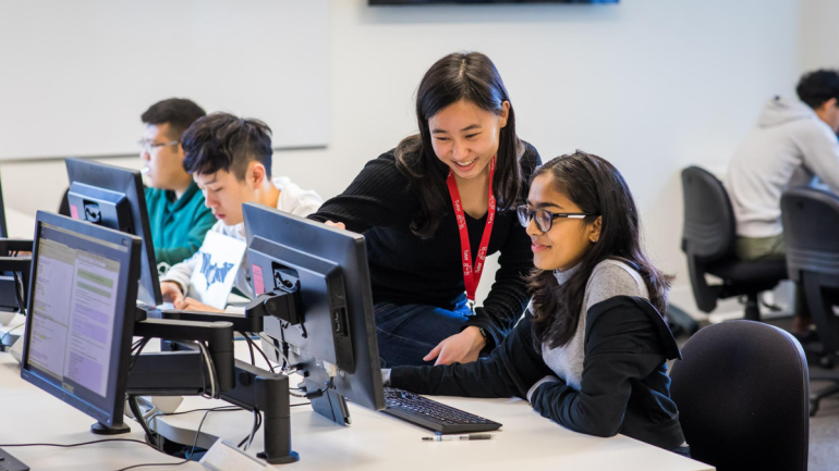 Teacher and students looking at computer and smiling